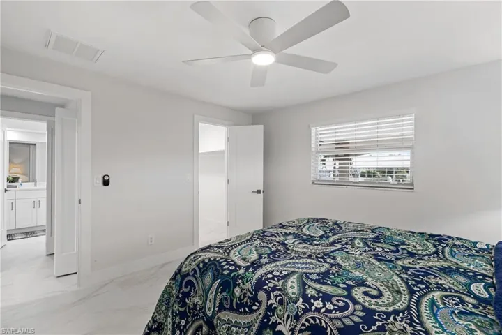 Bedroom featuring light marble finish flooring, a spacious closet, and a ceiling fan
