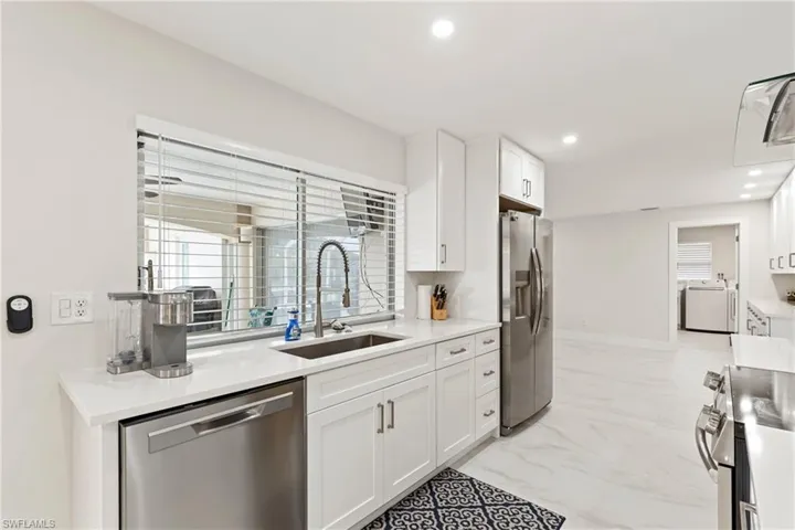 Kitchen with white cabinetry, appliances with stainless steel finishes, light marble finish flooring, recessed lighting, and light stone counters