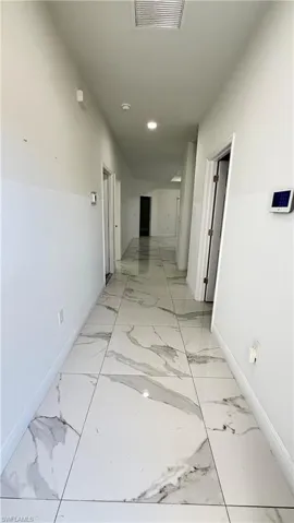 Corridor featuring baseboards and light marble finish flooring