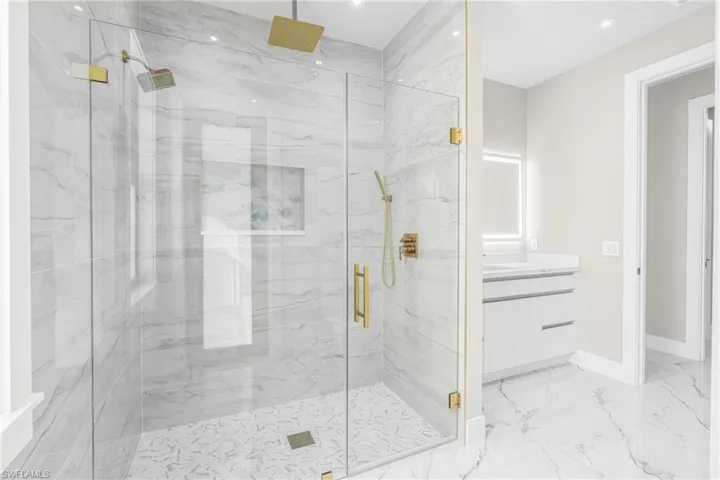 Full bathroom featuring a marble finish shower, vanity, recessed lighting, and light marble finish floors