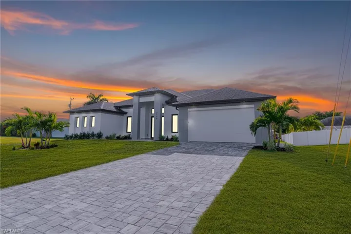 Prairie-style house with stucco siding, decorative driveway, and a garage