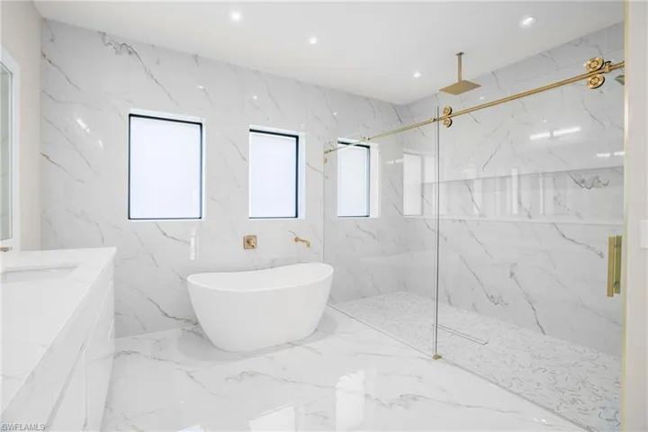 Bathroom with a marble finish shower, a freestanding tub, recessed lighting, vanity, and marble tiled floors