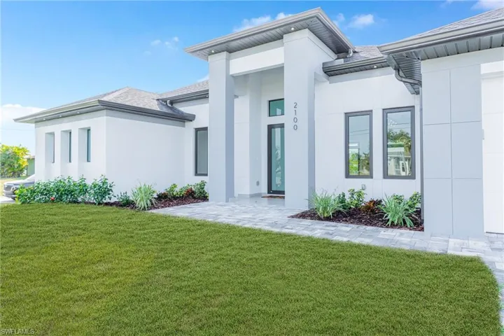 View of front of property with a front yard, stucco siding, and roof with shingles