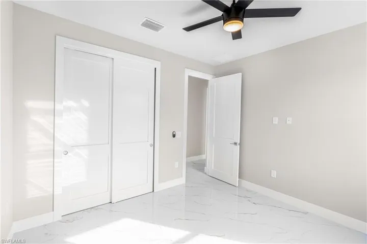 Unfurnished bedroom with a closet, light marble finish flooring, and ceiling fan