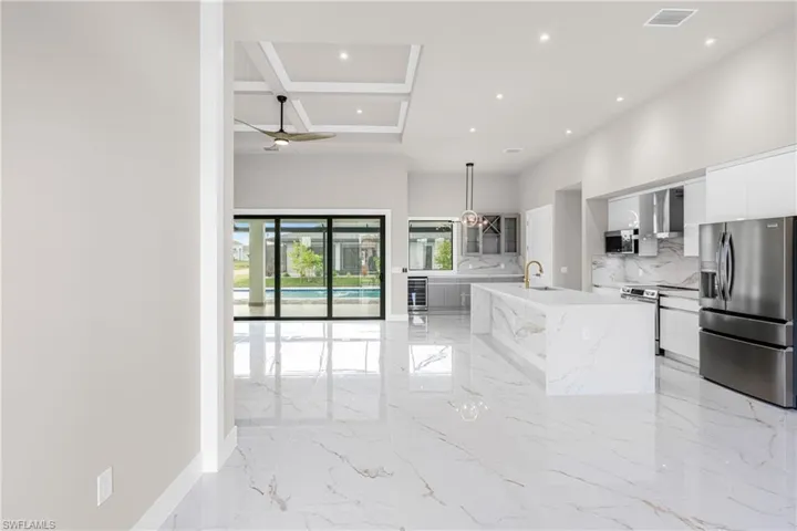 Kitchen featuring stainless steel appliances, coffered ceiling, modern cabinets, a towering ceiling, and recessed lighting