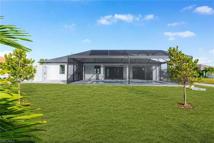 Rear view of house featuring glass enclosure, a sunroom, a lawn, and an outdoor pool