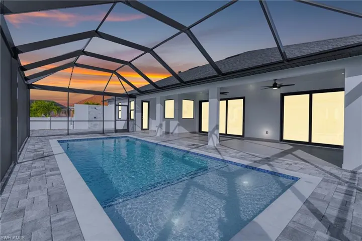 View of swimming pool featuring a sunroom, glass enclosure, and a patio