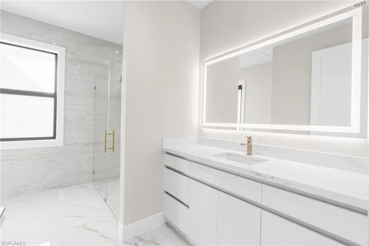 Full bathroom with a marble finish shower, vanity, and light marble finish floors