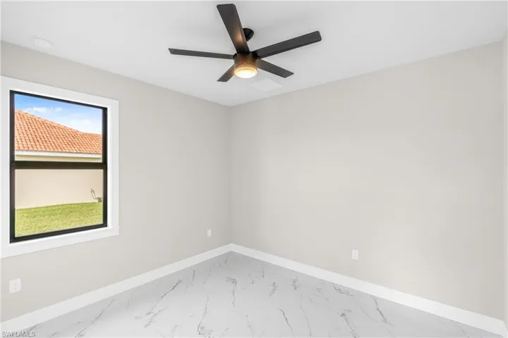 Unfurnished room with marble look tile flooring and ceiling fan