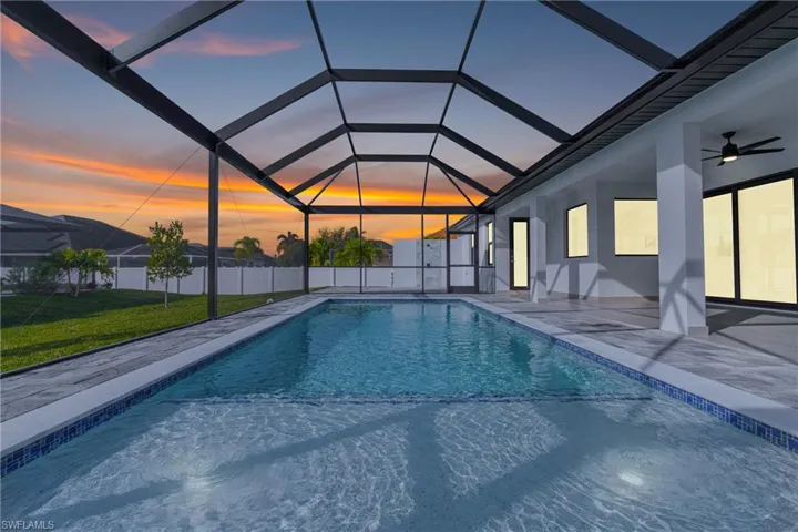 Pool at dusk featuring a lanai, a sunroom, and a patio area