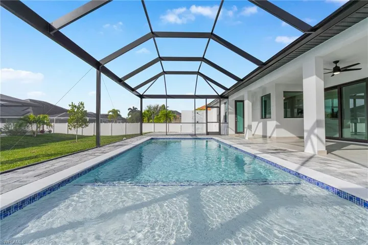 View of swimming pool with a sunroom, glass enclosure, and a patio