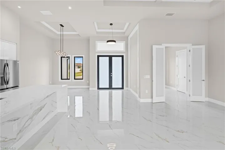 Foyer entrance with a raised ceiling, a towering ceiling, and light marble finish floors