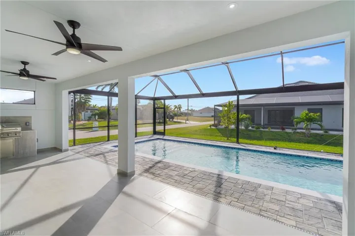 Swimming pool featuring a lawn, a lanai, a patio, and a sunroom