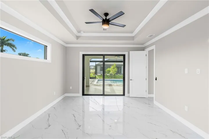 Spare room with healthy amount of natural light, light marble finish floors, a ceiling fan, and ornamental molding