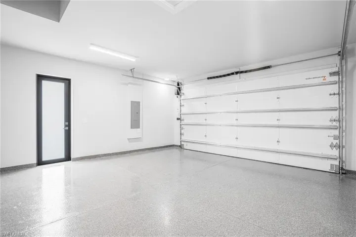 Garage with baseboards and electric panel