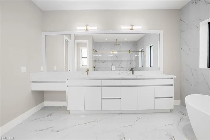 Bathroom with a marble finish shower, double vanity, a soaking tub, and light marble finish floors