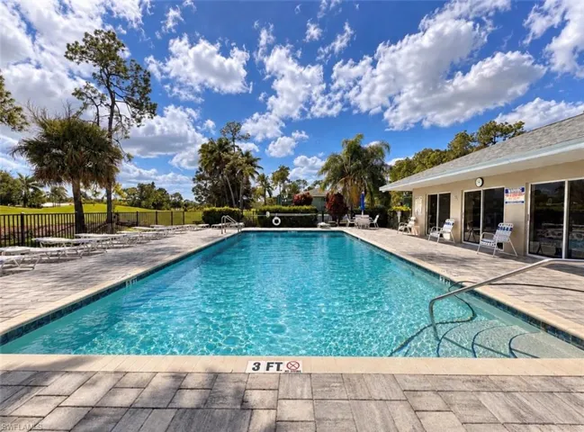 Rectangular swimming pool featuring a tile border, stone-paver decking, metal perimeter fencing, and sliding glass door access