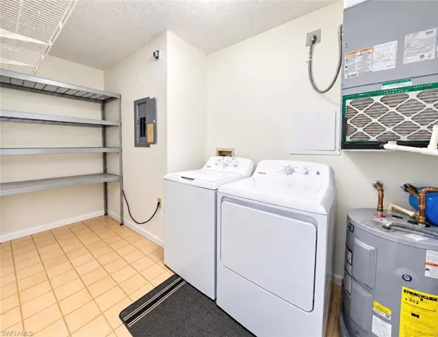 Utility room featuring new washer and dryer, built-in metal shelving, and integrated water heating and air filtration systems