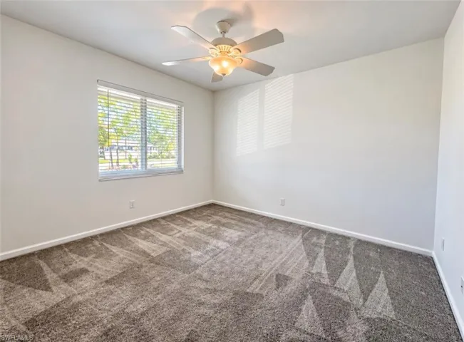 Room featuring neutral wall tones, wall-to-wall carpeting, an integrated ceiling fan with light fixture, and a window with horizontal blinds