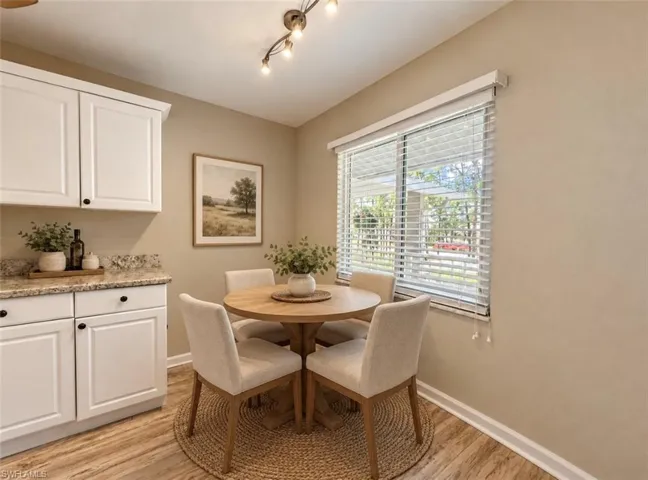 **Virtually staged Built-in white cabinetry with speckled stone-finish countertops, wood-finish flooring, and a multi-light track fixture