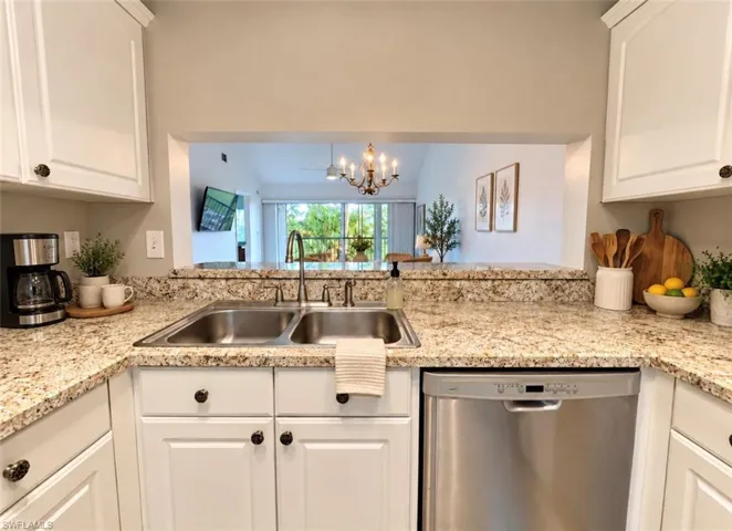 Kitchen featuring white shaker-style cabinetry, stone-surface countertops, double-basin stainless steel sink, gooseneck faucet, and stainless steel dishwasher
