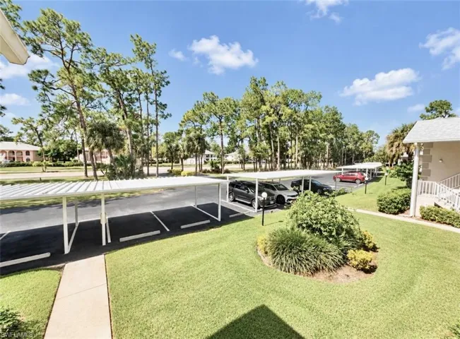 Covered parking structures, paved parking area, manicured lawn, and mature trees