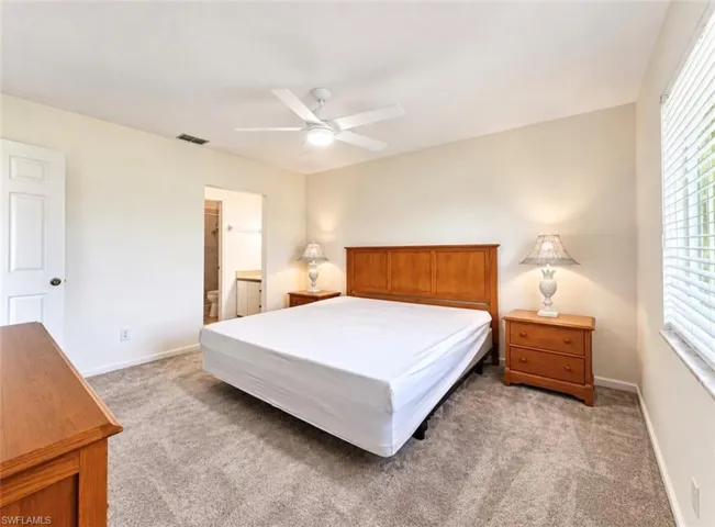 Neutral-toned room featuring neutral wall-to-wall carpeting, white-painted doors, a white ceiling fan with integrated lighting, and horizontal window blinds