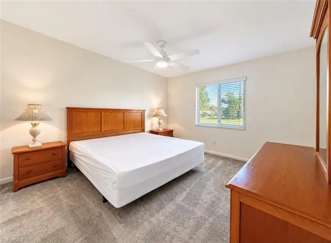 Neutral-toned interior space featuring neutral wall-to-wall carpeting, a multi-blade ceiling fan with integrated light fixture, and horizontal blind window treatment
