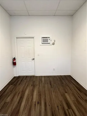 Spare room featuring an AC wall unit, a paneled ceiling, and dark hardwood / wood-style flooring