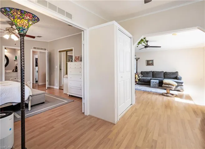Bedroom with light wood-type flooring, crown molding, and a ceiling fan