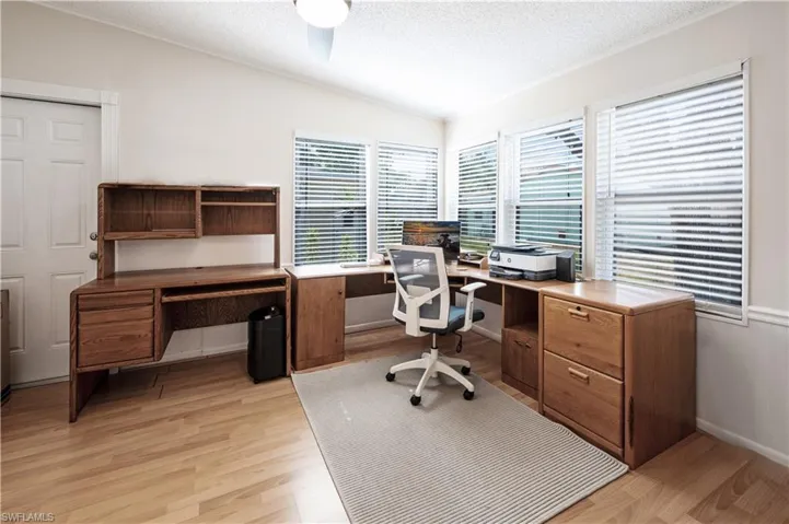Home office featuring light wood-style flooring, a textured ceiling, and ornamental molding