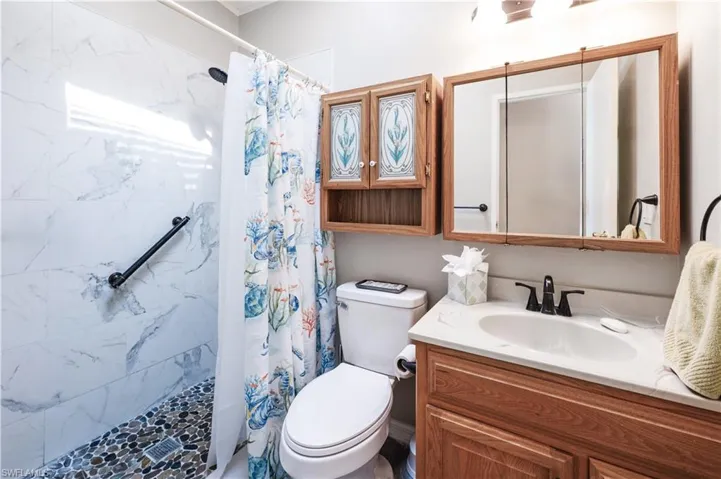 Full bath with a tile shower, toilet, and vanity