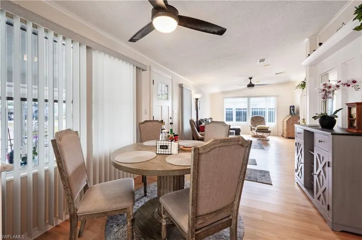 Dining area with ceiling fan, a textured ceiling, ornamental molding, and light wood-style floors