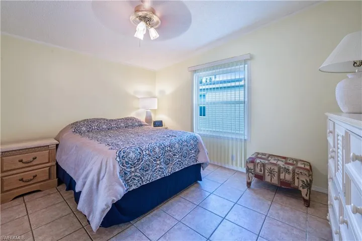 Bedroom with light tile patterned floors, ceiling fan, and crown molding