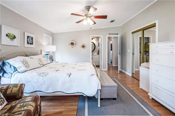 Bedroom with light wood-style floors, a closet, ensuite bathroom, and ceiling fan
