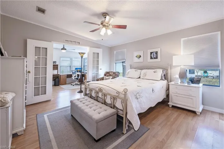 Bedroom with french doors, vaulted ceiling, light wood-style flooring, a textured ceiling, and a ceiling fan