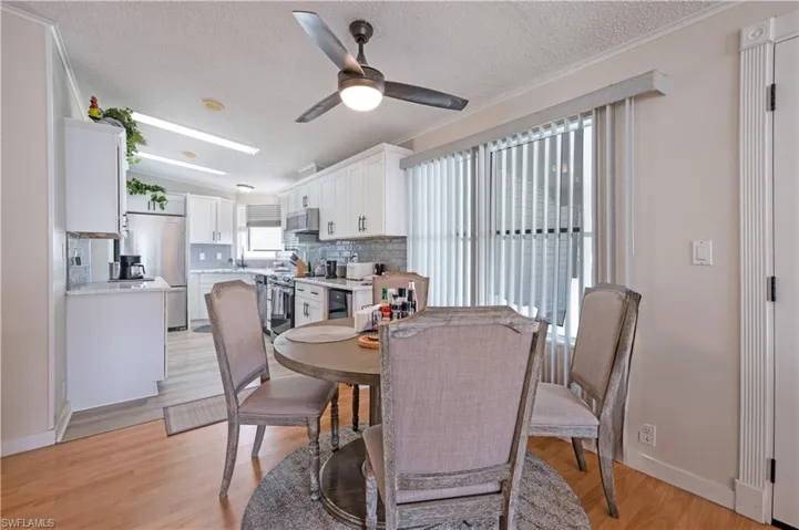 Dining area featuring ceiling fan, a textured ceiling, baseboards, and light wood-style flooring