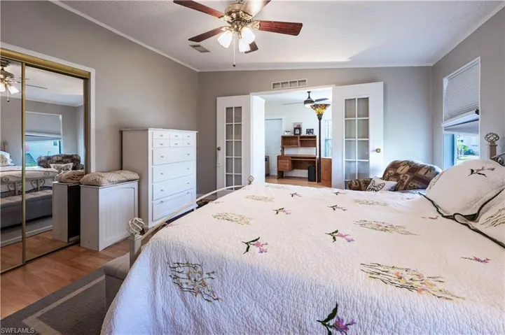 Bedroom featuring a closet, ornamental molding, ceiling fan, and parquet floors