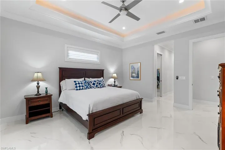 Bedroom featuring a tray ceiling, marble finish floor, visible vents, and baseboards