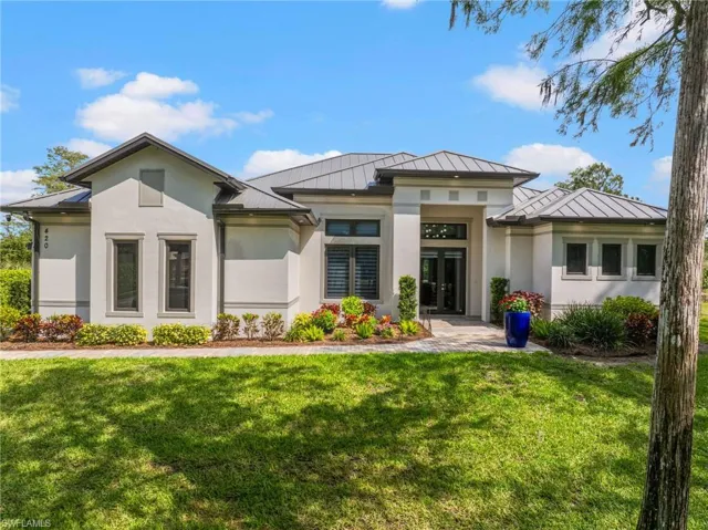View of front of home with metal roof, a standing seam roof, a front yard, and stucco siding