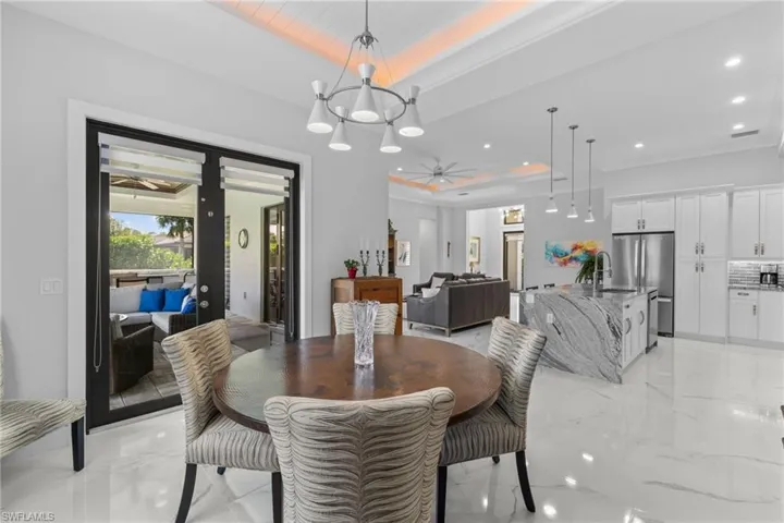 Dining area featuring recessed lighting, a raised ceiling, marble finish floor, and french doors