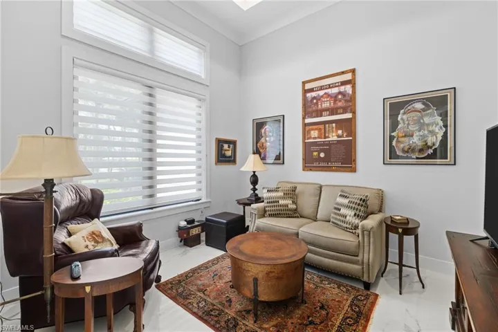 Living area with marble finish floor, plenty of natural light, and ornamental molding