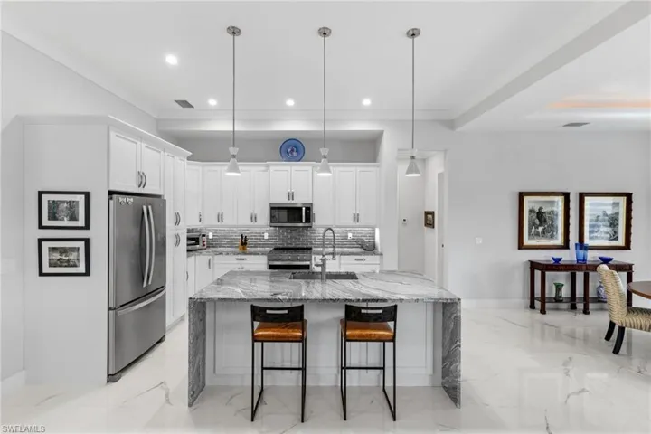 Kitchen featuring a sink, white cabinets, marble finish floor, appliances with stainless steel finishes, and tasteful backsplash