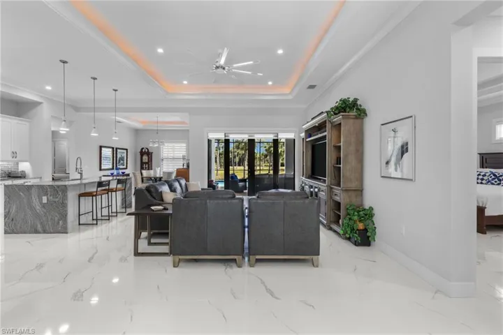 Living area with recessed lighting, a ceiling fan, baseboards, marble finish floor, and a raised ceiling