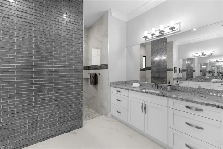 Full bath with a walk in shower, marble finish floor, vanity, and crown molding