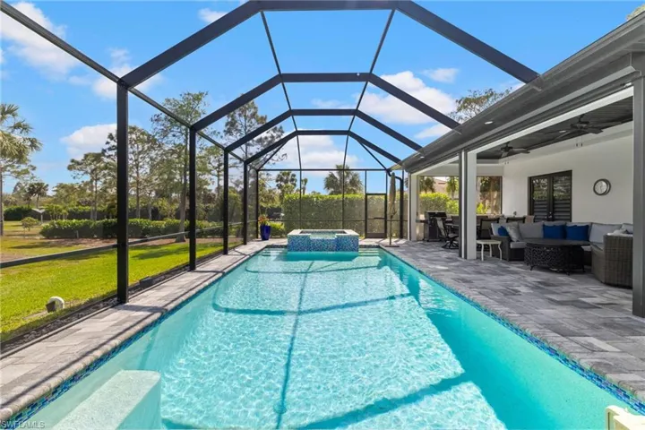 View of swimming pool featuring ceiling fan, outdoor lounge area, a pool with connected hot tub, a lawn, and a patio area
