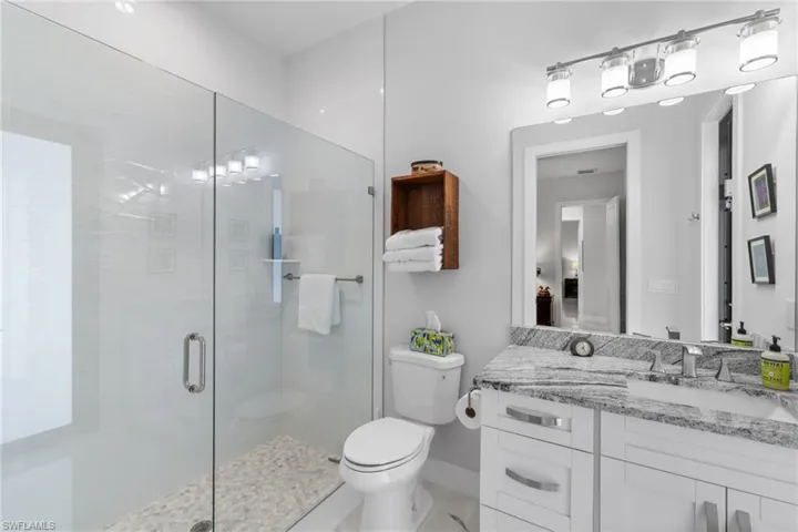 Full bath featuring vanity, a shower stall, and toilet