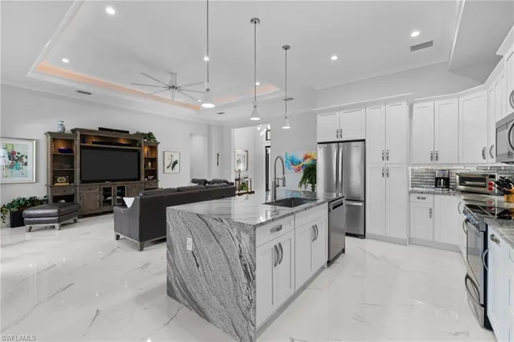 Kitchen with marble finish floor, stainless steel appliances, a sink, and a raised ceiling