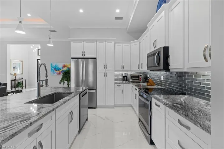 Kitchen with appliances with stainless steel finishes, marble finish floor, a sink, and ornamental molding