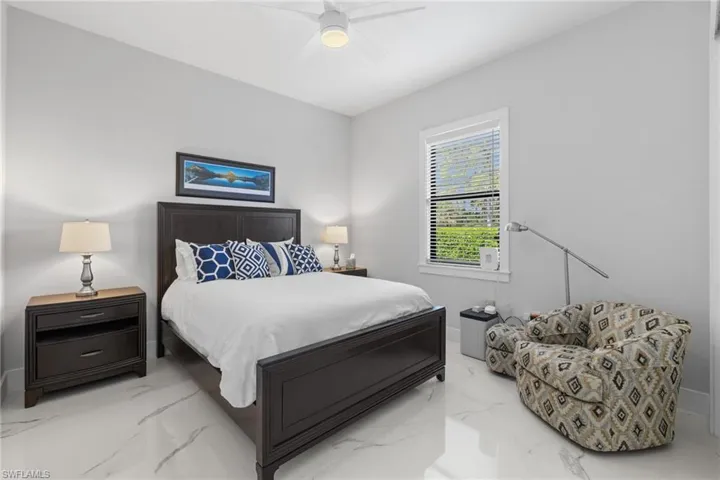 Bedroom with ceiling fan, marble finish floor, and baseboards